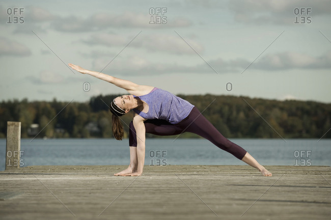Woman practicing yoga on jetty, Woerthsee, Bavaria, Germany