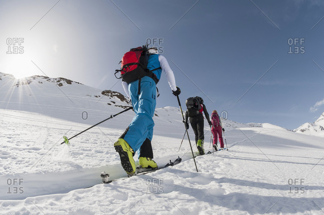Three skiers climbing steep slope snow winter
