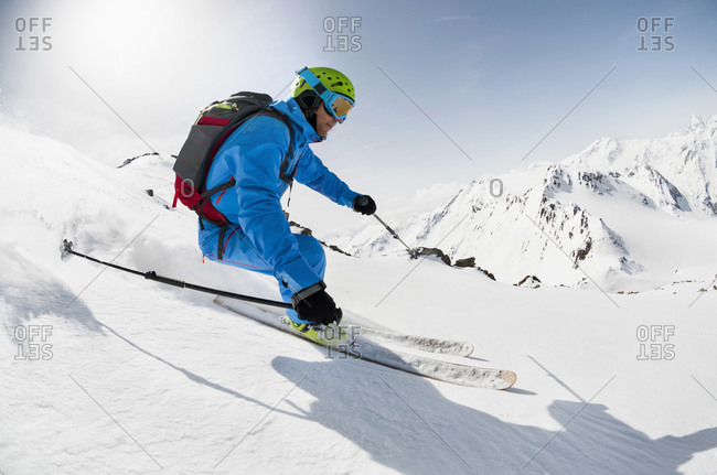 Man skier skiing downhill steep slope Alps