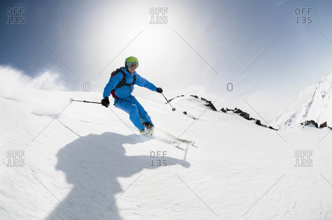 Man skier skiing downhill steep slope sunshine