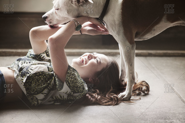 Young woman plays with dog on floor