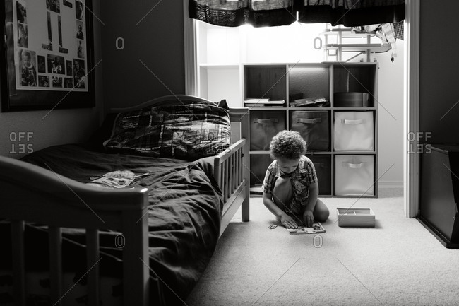 Young boy playing on bedroom floor by light of the closet