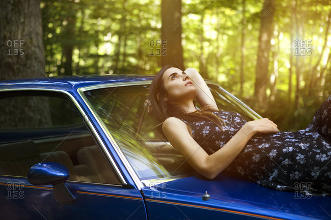Woman lying on car hood