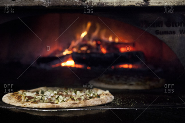 Sausage Pizza with mozzarella cooks in a wood-fire oven