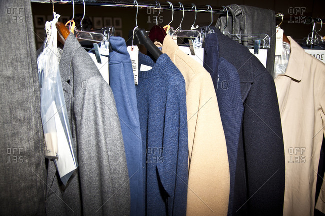 Sweaters and coats hanging on a clothing rack at a fashion show