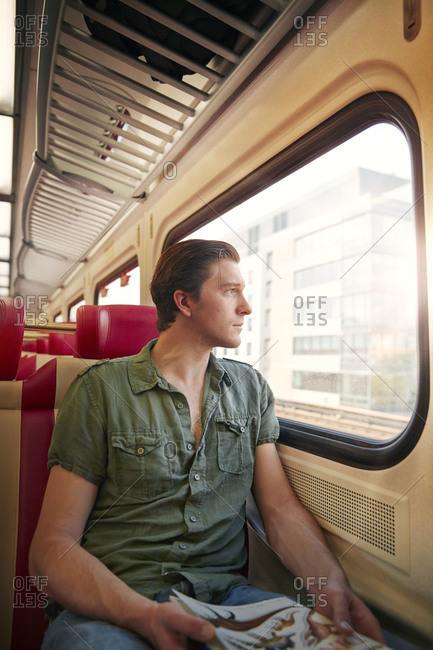 Young man staring out of a train window