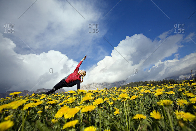 A woman practices yoga in a flower field