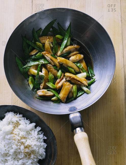 Chicken with snow peas and green onions stir fry in wok