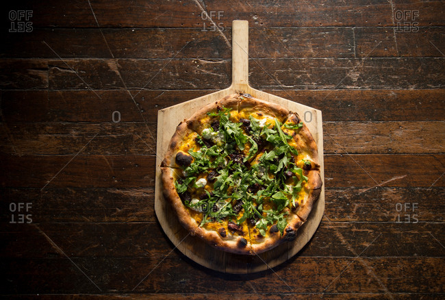 Balsamic-braised bacon pizza with roasted butternut squash puree, goat cheese, and arugula on pizza peel