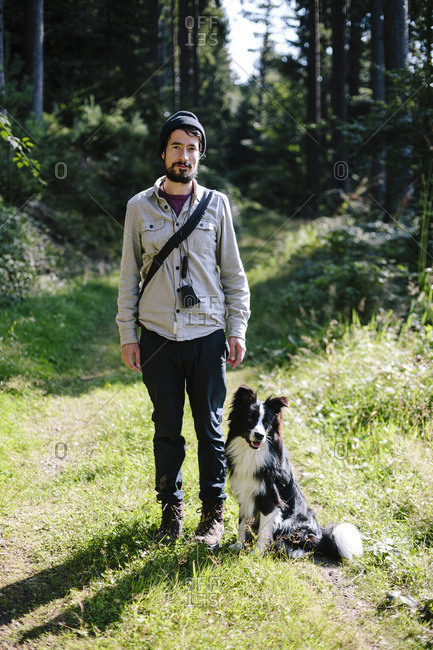 Man with Border Collie on forest path