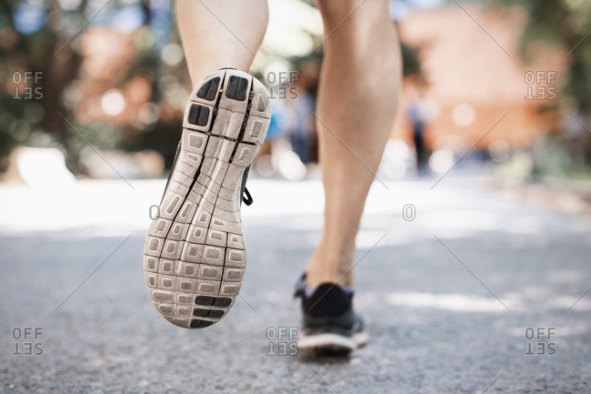 Low section of woman in sports shoes running on park street