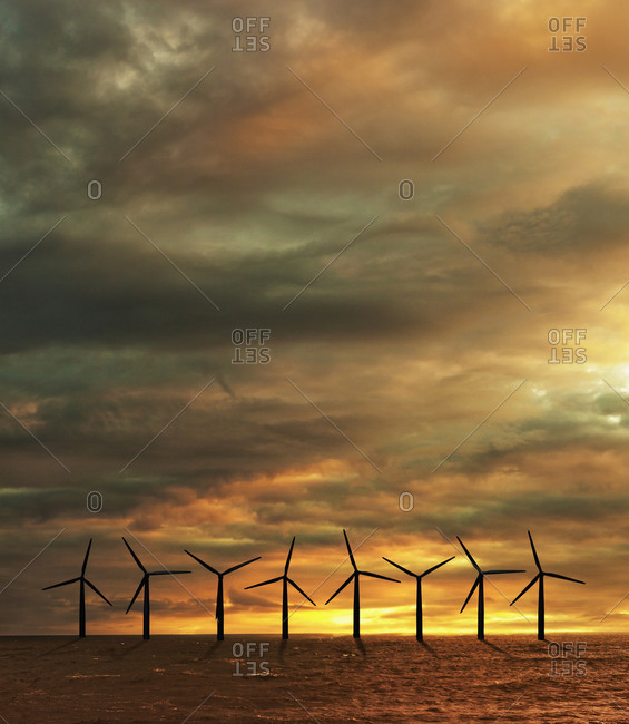 Wind turbines in sea at sunset