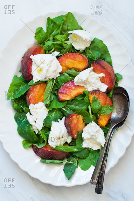 Top view of summer salad of grilled peaches, buffalo mozzarella and baby spinach