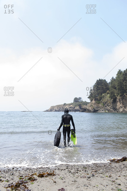 Man walking into the sea with diving equipment