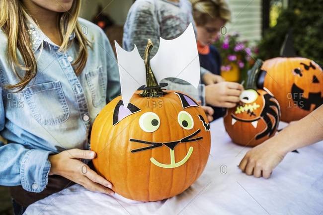 Young girl decorating a pumpkin for Halloween