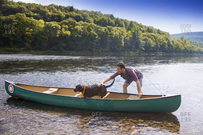 Dog in canoe with man standing in river