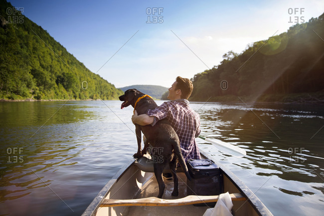 Man hugging dog in canoe