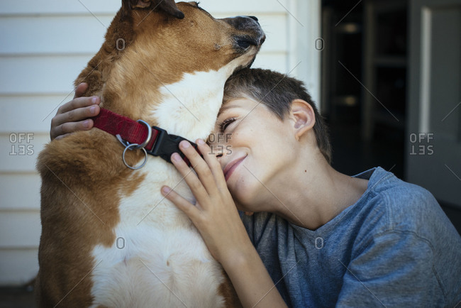 Boy and dog hugging on a porch
