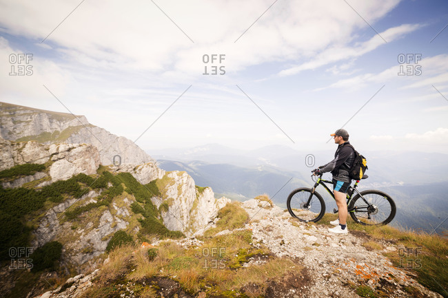 Bicyclist looking out over valley from mountain, Carpathian Mountains