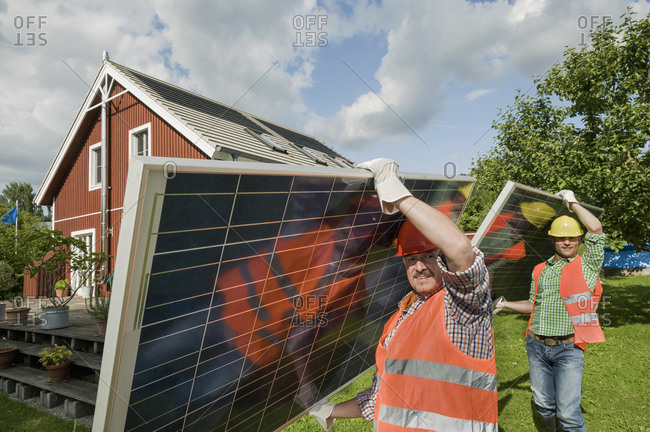 Workmen delivering solar panel house garden