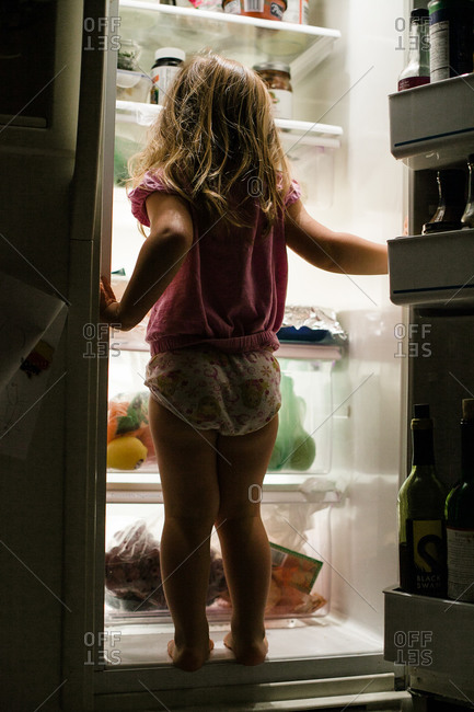 Young girl standing in fridge door