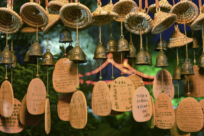 Lucky charms in form of small bells, wicker hats and wooden plates with Chinese hand writing at Shenyuan in Shaoxing