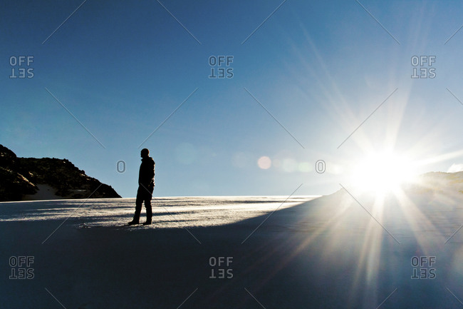 A climber enjoys the sunrise from a snowfield in the alpine near Chilliwack, BC, Canada