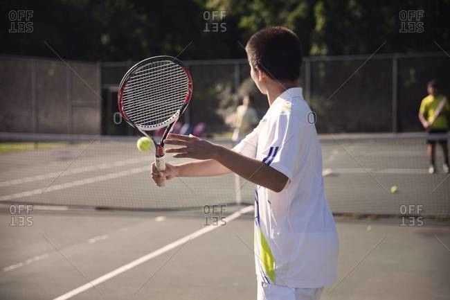 Boy ready to backhand ball during tennis match