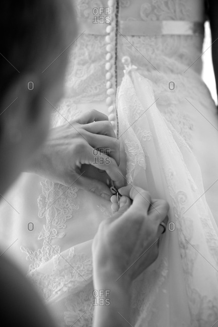 Woman helping bride do up her dress before the wedding