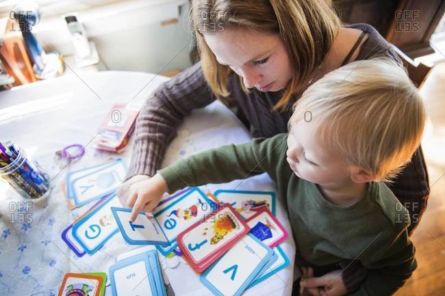 Young woman teaching her son with alphabet flash cards