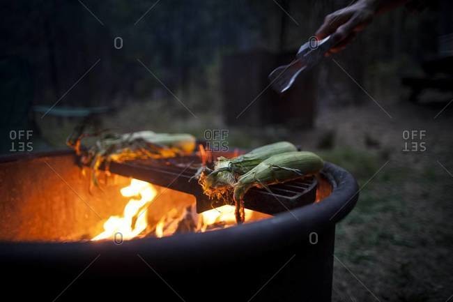 Man grilling corn at a campsite