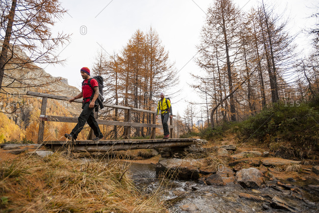 Two men crossing a bridge while hiking in Devero National Park, Ossola, Italy