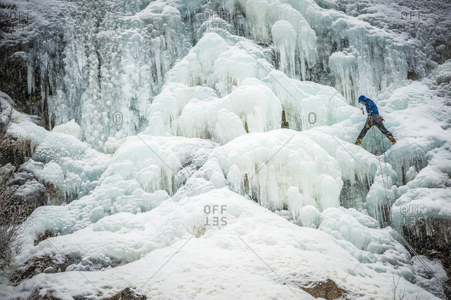 Man lead climbing an ice fall in the middle of a snow storm in Chamonix, France