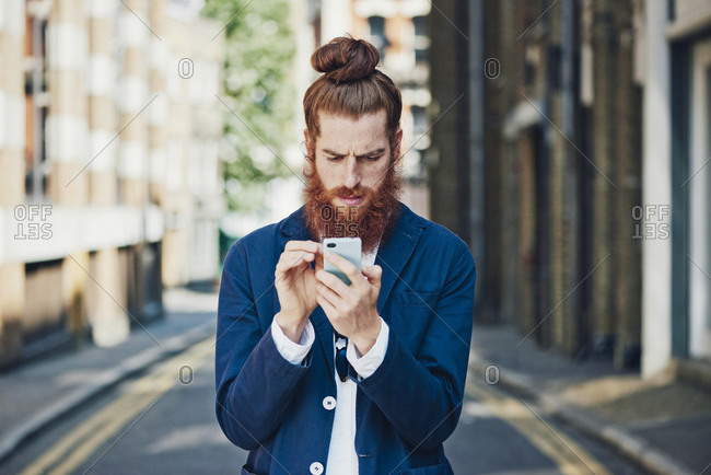 Man in sports coat in street looking at phone