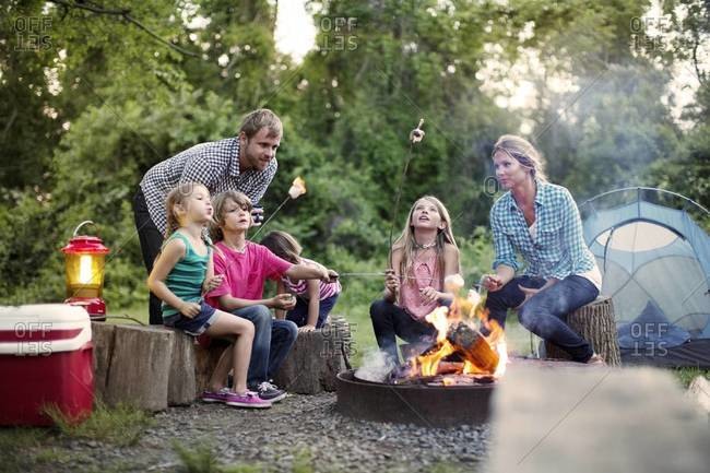 Family roasting marshmallows over campfire