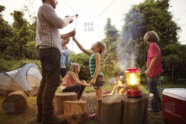 Family roasting marshmallows over campfire