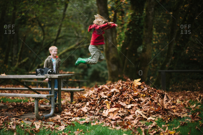 Girl leaping into leaf pile from picnic table