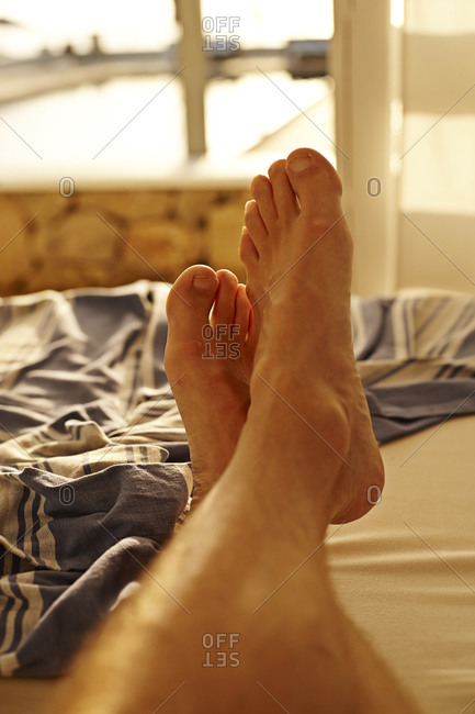 Man\'s feet lounging on resort bed