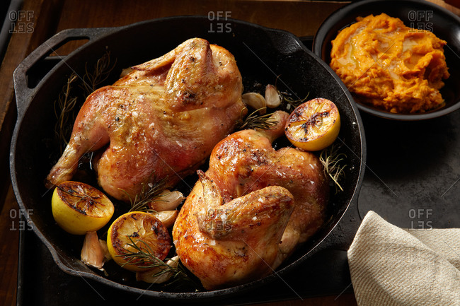 Halved chicken roasting in a cast-iron pan