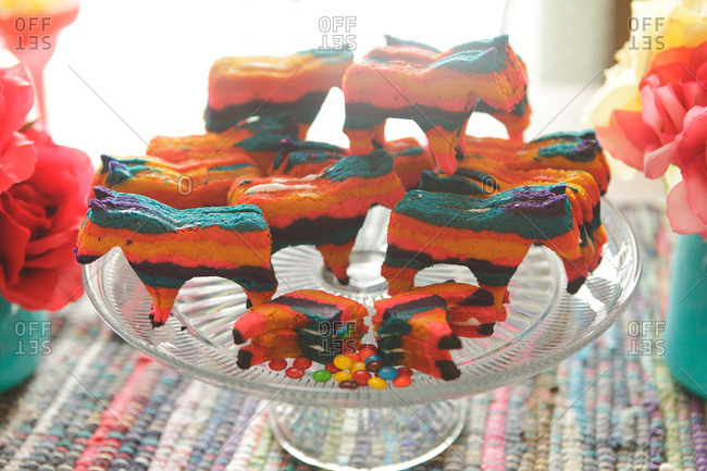 Horse-shaped rainbow cookies on a cake stand