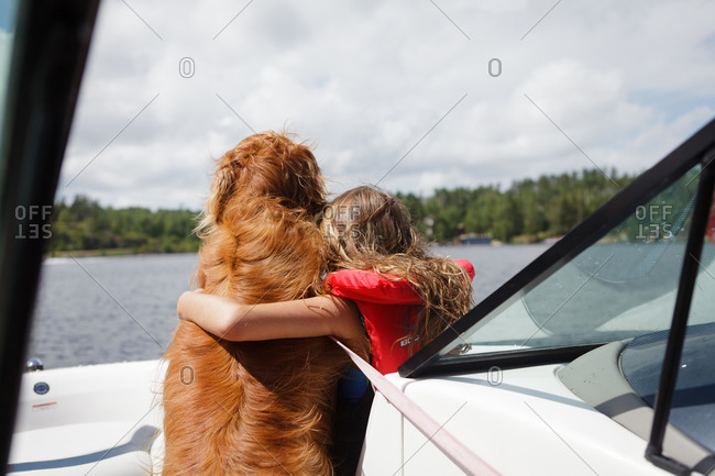 Young girl hugging a dog on a boat