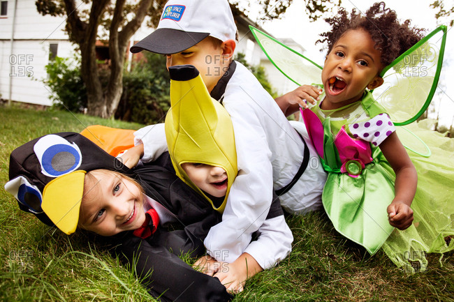 Kids in Halloween costumes wrestling in yard