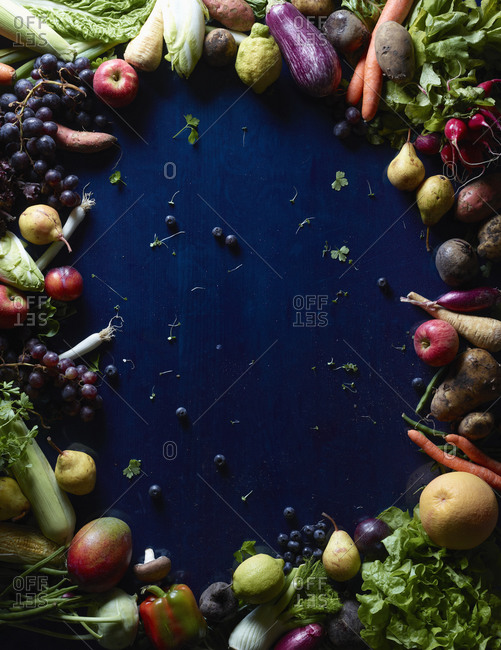 Fresh vegetables and fruits forming circle on blue table