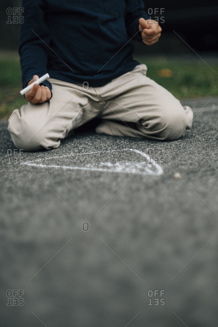 Boy with chalk drawing on pavement