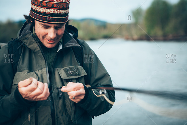 Close up of man fly-fishing, tying hook to line, Hoh River in background, Olympic NP, WA, USA