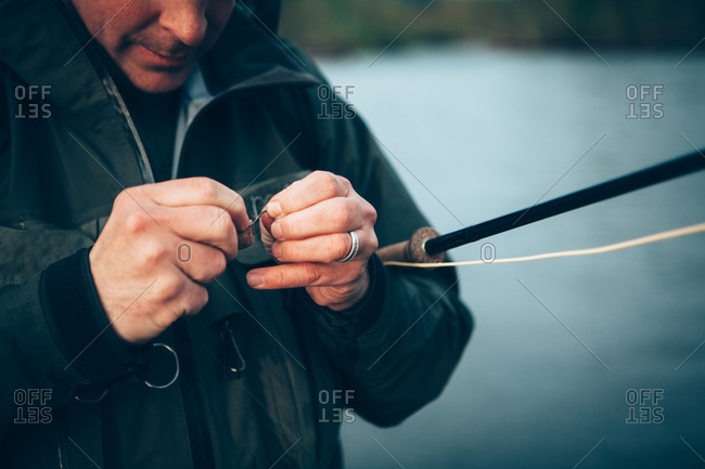 Close up of man fly-fishing, tying hook to line, Hoh River in background, Olympic NP, WA, USA