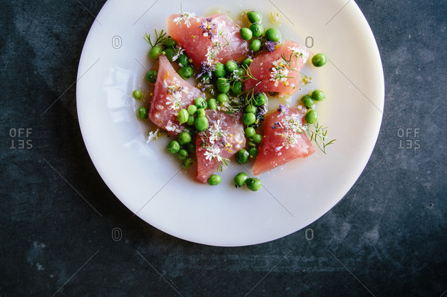Raw fish topped with flowers and peas