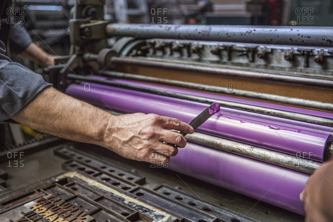 Pan spreading purple paint on print machine