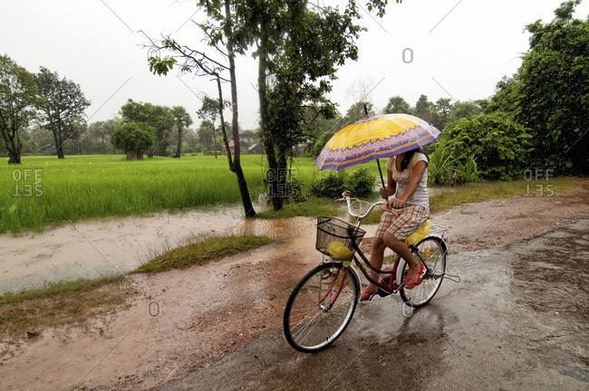 Woman riding a bicycle with an umbrella in Siem Reap, Cambodia