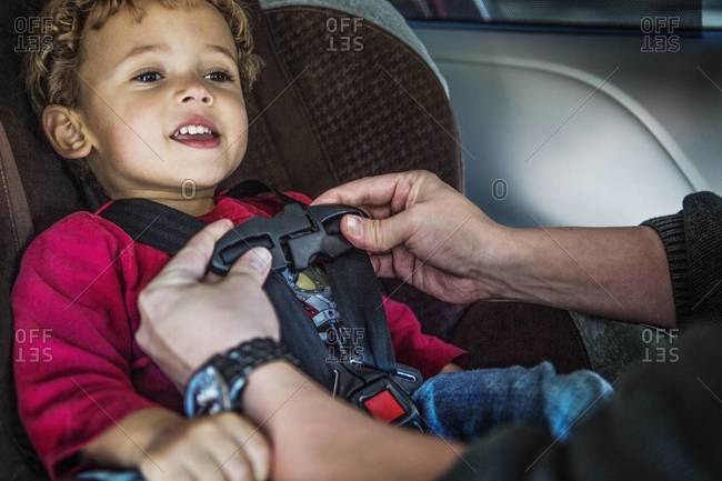 A dad buckles his son into a car seat